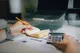 Calculadora e moedas sobre mesa com documentos financeiros, luz natural lateral